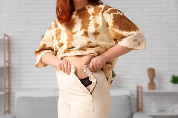 Image of woman trying to do her trousers up after pregnancy weight gain Rushden