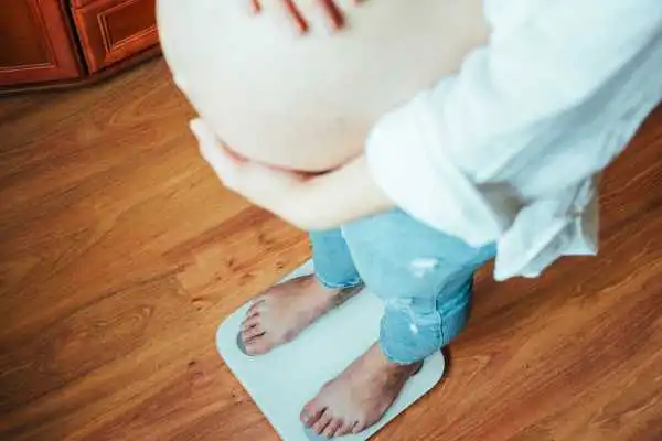 Image of woman weighing herself and experiencing weight gain through pregnancy Rushden
