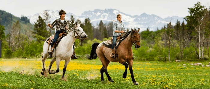 Confident plus-size woman riding Rushden a horse through a field with a smile on her face.